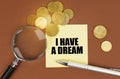 On a brown surface are coins, a pen, a magnifying glass and stickers with the inscription - I have a Dream Royalty Free Stock Photo