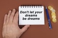 On a brown surface are coins, a pen and a notepad with the inscription - dont let your dreams be dreams Royalty Free Stock Photo