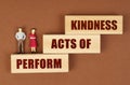 On a brown surface, wooden blocks with the inscription - Perform Acts of Kindness, there are figures of people. Royalty Free Stock Photo