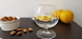 Brown table with brande glass, roasted almonds and lemons slices Royalty Free Stock Photo