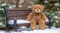 A brown teddy bear with a bow tie sits on a snow-covered park bench Royalty Free Stock Photo