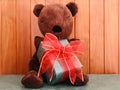 A brown teddy bear holding a Green gift box with red ribbon. Royalty Free Stock Photo