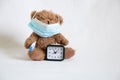 brown teddy bear in a medical mask with a thermometer and a watch is standing nearby, childhood morbidity, illness