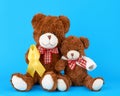 brown teddy bear sits and holds in his paw a yellow silk ribbon on a blue background Royalty Free Stock Photo