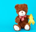 brown teddy bear sits and holds in his paw a yellow silk ribbon Royalty Free Stock Photo