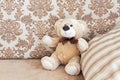 Brown teddy bear sitting on beige cozy sofa with pillows in the background Royalty Free Stock Photo
