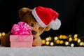 Brown teddy bear wearing santa claus hat holding blurred focus of Christmas gift box Royalty Free Stock Photo