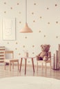 Brown bear on wooden chair next to small table in scandinavian kid`s playroom with wooden furniture Royalty Free Stock Photo