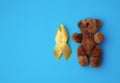 brown teddy bear and yellow silk ribbon on a blue background Royalty Free Stock Photo