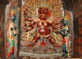 Brown Tibetan deity statue in a golden crown with six arms in a monastery