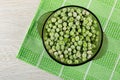 Brown transparent bowl with frozen green peas on napkin on table. Top view Royalty Free Stock Photo