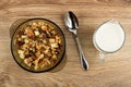 Brown bowl with granola, spoon, pitcher with yogurt on wooden table. Top view Royalty Free Stock Photo