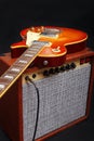 Brown tube combo amplifier for electric guitar with honey sunburst guitar on black background Royalty Free Stock Photo