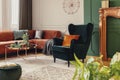 Velvet corner sofa and emerald green wing back chair in classy living room Royalty Free Stock Photo