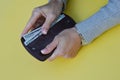 Female hands holding a brown wallet with banknotes, a hand taking money out of a wallet  on a yellow background. A woman Royalty Free Stock Photo