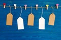 Blank paper price tags or labels set and wooden pins decorated on colored hearts hanging on a rope on the blue wooden background. Royalty Free Stock Photo