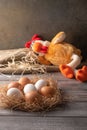 Brown and white chicken eggs in a straw nest on wooden background. Next to a chicken toy sleeping. Vertical orientation Royalty Free Stock Photo