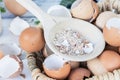 Brown and white crushed eggshells in wooden spoon on whole eggshells in basket on white table Royalty Free Stock Photo