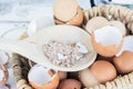 Brown and white crushed eggshells in wooden spoon on whole eggshells in basket on white table Royalty Free Stock Photo