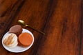 Brown and white french macarons or macaroons in a plate with a golden tea spoon over a vintage wooden background Royalty Free Stock Photo