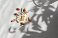 Brown and white supplement and vitamin capsules on white marble background with floral sunlight shadows. Medicine