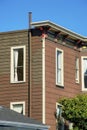 Brown wood panneled building with horizontal timber and visible rain gutter pipe with flat roof and white accent window