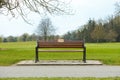 Brown wooden bench with a green meadow in the background. Lonely chairs on the lawn in the park. Royalty Free Stock Photo