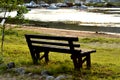 Brown wooden bench in the park. Summer sunny day. Green grass and trees. Resting and relaxing area. Empty bench for Royalty Free Stock Photo