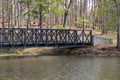 A brown wooden bridge over a rippling lake surrounded by lush green trees at Murphey Candler Park