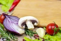 Brown wooden cutting board with summer vegetables and champignon mushroom on table background. Royalty Free Stock Photo