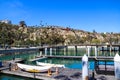 A brown wooden dock with boats parked at the dock, a long brown wooden pier surrounded by a cliff with beach front homes on top Royalty Free Stock Photo