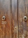 Brown wooden door with door pulls. Aged. Double wing. Solid