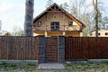 A brown wooden fence and a closed door and part of a large house