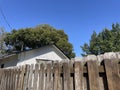 Brown wooden fence shadow box style blue sky summer background house roof Royalty Free Stock Photo