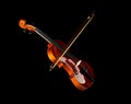 Brown wooden fiddle or violin, classic musical instrument, with bow isolated over black background