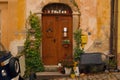 Brown wooden front door, old yellow house facade, ivy , many flowers and porcelain cups.