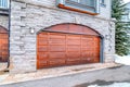 Brown wooden garage door with arched design of home with stone brick wall