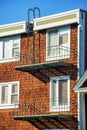 Brown wooden house with white accent paint around windows and visible black metal balconies with escape ladder and flat