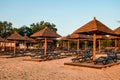Brown wooden loungers and umbrellas on empty sandy beach Royalty Free Stock Photo