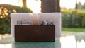 A brown wooden napkin holder and toothpicks sit on the glass table of the cafe, illuminated by the sun`s rays. Table setting in