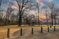 A brown wooden pergola near a silky green lake in the park surrounded by yellow winter grass and bare winter trees with blue sky Royalty Free Stock Photo