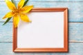 Brown wooden photo frame with yellow flowers lily on old blue shabby background Royalty Free Stock Photo