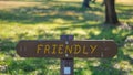 Brown wooden sign in grassy field with friendly written on it