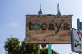 A brown wooden sign with two curved lights at Tocaya Modern Mexican with lush green trees and street signs in Venice California Royalty Free Stock Photo