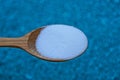 Brown wooden spoon with white salt on a blue background Royalty Free Stock Photo