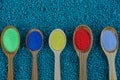 Brown wooden spoons with colored powder on blue stones Royalty Free Stock Photo