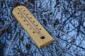 A wooden thermometer lies on the branches of plants in frost and snow Royalty Free Stock Photo