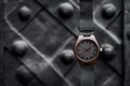Brown wooden wrist watch with a leather strap on a black abstract background. Close-up. Space for text Royalty Free Stock Photo