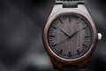 Brown wooden wrist watch with a leather strap on a black abstract background. Close-up. Space for text Royalty Free Stock Photo