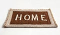A brown woven rug mat with the word text HOME written on it in white letters